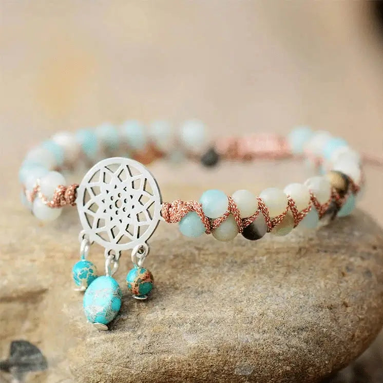 Bohemian style macrame bracelet featuring light blue and white Amazonite gemstone beads, accented with a silver-plated dream catcher charm and dangling turquoise charms.