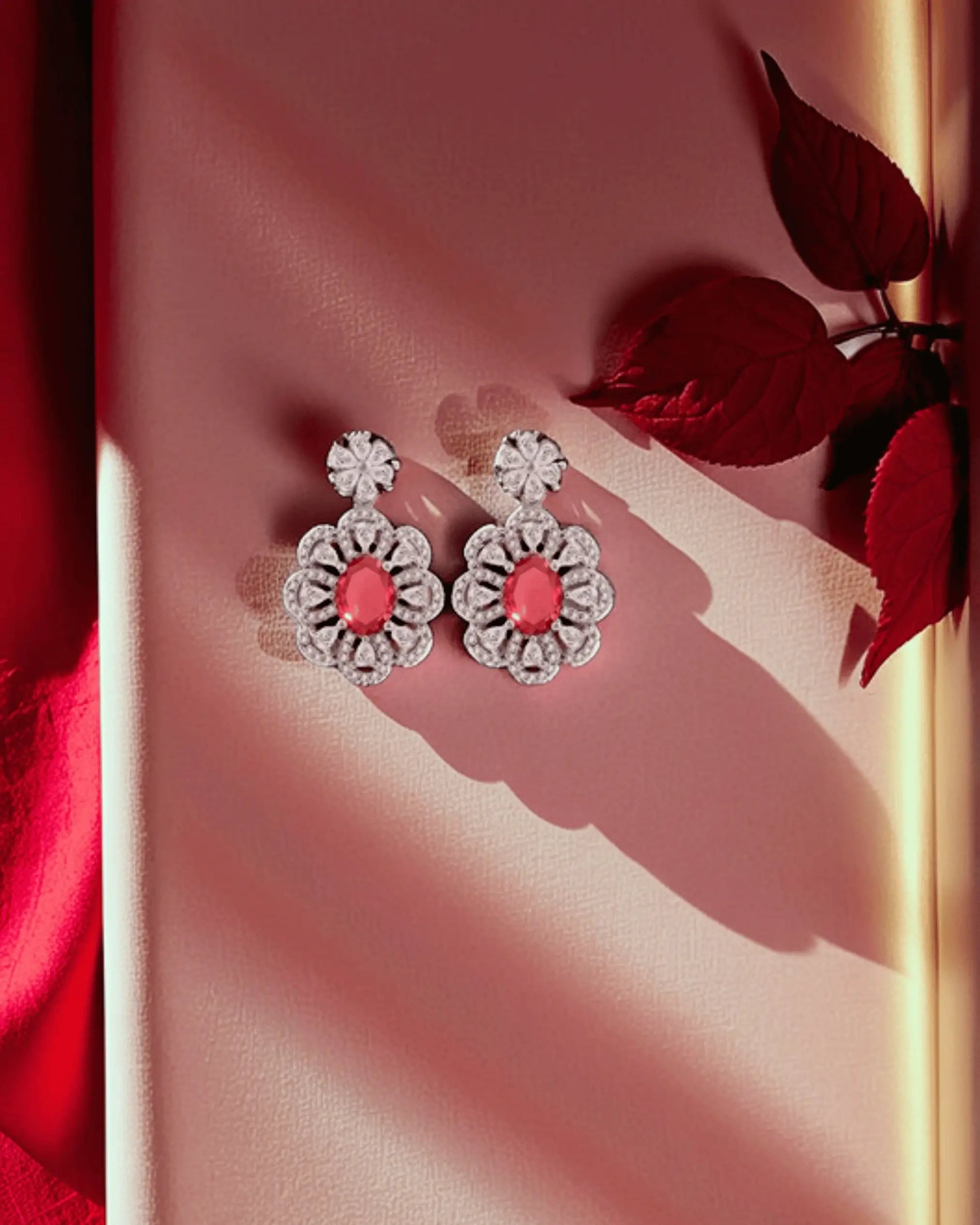 Pair of luxury dangle earrings with a silver floral cluster setting, featuring a vivid pink center stone and a halo of sparkling white crystals.
