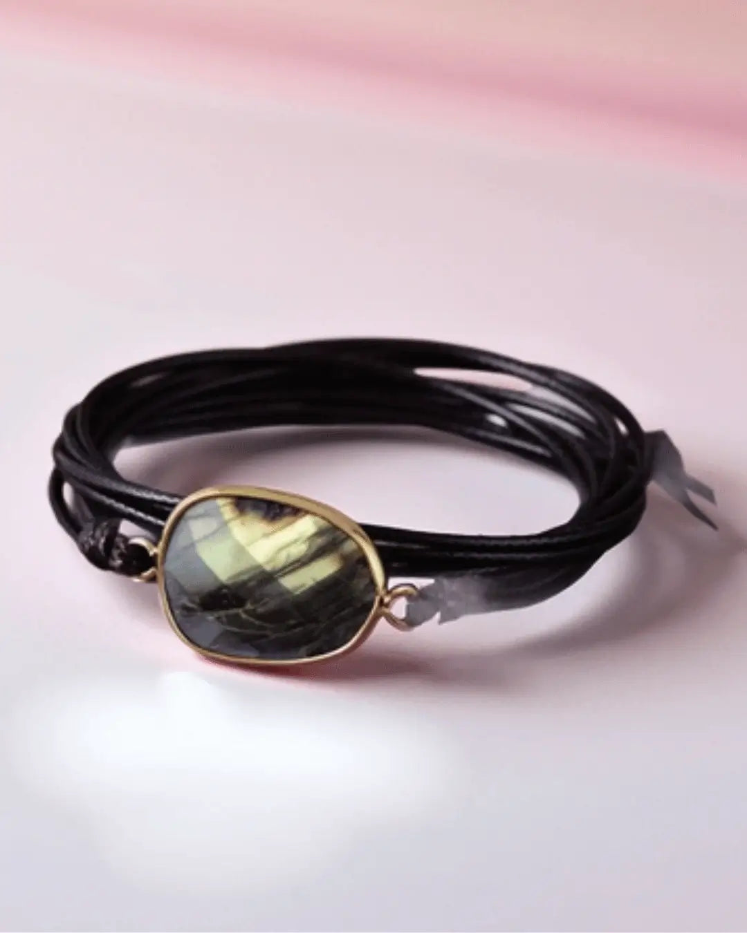 Black leather multi-wrap bracelet featuring a bezel-set, faceted Labradorite stone with gold flash, secured by a gold-tone metal loop.