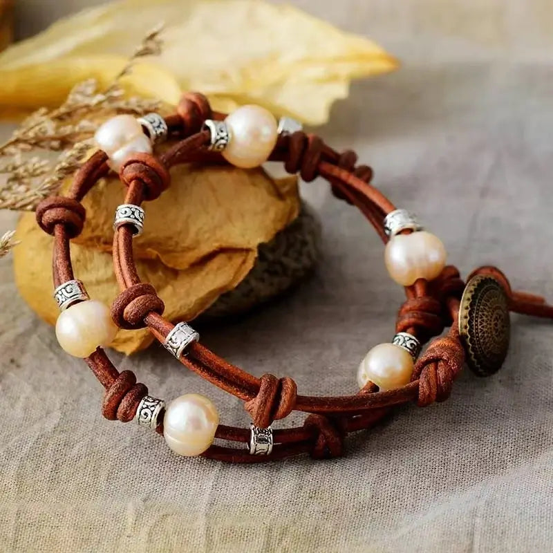 Double-wrap bohemian bracelet featuring knotted brown leather cords, freshwater pearls, and antique silver spacer beads, secured with a bronze button clasp.