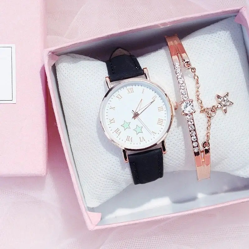 Women's watch and bracelet gift set, featuring a rose gold star-dial watch with a black leather strap, packaged next to a matching star charm bangle in a pink box.